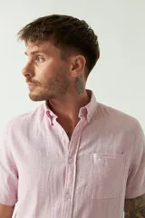 Camisa de manga corta color beige claro, confeccionada en lino y algodón, con cuello abotonado, bolsillo en el pecho y logo bordado. Corte semi slim.