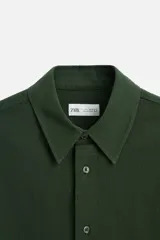 Camisa azul marino de algodón con textura jacquard, corte relaxed fit, cuello solapa, manga larga con puños abotonados y cierre frontal con botones.
