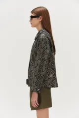 Campera de cuero con estampado de reptil, corte amplio, hombros caídos, largo a la cintura y cinturón.