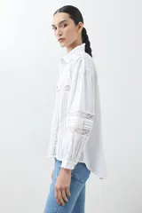 Camisa blanca de manga larga con detalles de encaje en el frente y las mangas.