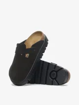 Sandalias cerradas de gamuza negra con plantilla anatómica de corcho-látex y suela de goma con plataforma. Presentan una tira ancha ajustable con hebilla metálica.