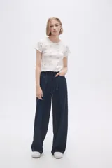 Remera blanca con estampado de moños rosas y lunares. Tiene cuello redondo y mangas cortas con terminación ondulada.