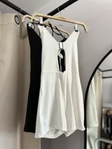 Catsuit corto con escote halter y abertura en el abdomen, con tiras finas para atar en la nuca y en la espalda.