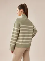 Polera de punto con rayas en tonos crema y beige, diseño de manga larga y cuello alto.