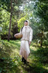 Cárdigan tejido a mano en una mezcla de lana merino y seda natural, color beige con detalles en blanco. Tiene una silueta holgada, manga caída, escote clásico, bordados artesanales y cierre con botones.