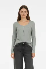 Remera manga larga de algodón, color verde claro, entallada, con cuello redondo y una hilera de botones en el escote. Incluye un pequeño logo bordado en el pecho.