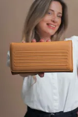 Billetera larga color mostaza de símil cuero con tapa y repartición con cierre. Compartimento con tarjeteros y bolsillos. Compartimento posterior incluye monedero con cierre, tarjeteros y billetes. Bolsillo atrás con cierre.