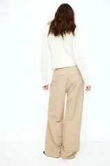 Pantalón color beige de lino con tiro alto, cintura elástica, bolsillos al bies y bolsillos traseros insertados. Piernas rectas con pliegue cosido adelante.