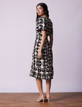 Vestido estampado con escote en V con frunces, cintura elastizada con lazo de ajuste y mangas cortas con detalles en broderie.