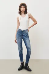 Pantalón jean de tiro medio, corte slim, color azul claro, con rotura en la rodilla y terminación desflecada.