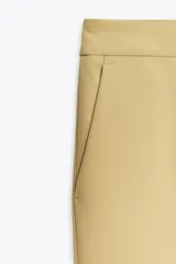 Pantalón color arena de tiro alto con bolsillos delanteros y corte acampanado. Cierre frontal con cremallera y gancho metálico.