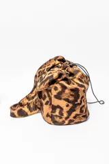Bolso tipo bombonera con estampado animal print de leopardo en tonos marrones. Tiene cierre con cordón ajustable y asa corta para llevar al hombro.
