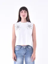 Musculosa blanca de corte recto, sin mangas y con cuello redondo. Presenta un diseño de estrellas con apliques de strass o tachas plateadas en la zona de los hombros.