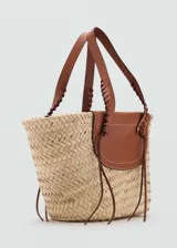 Bolso tipo canasta de fibras naturales color beige, con solapa y asas de cuero marrón.