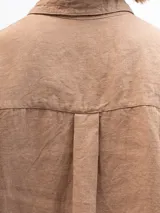 Camisa marrón claro de lino con mangas 3/4, cuello clásico, cierre frontal con botones, bolsillo de parche en el pecho y corte holgado. Marca Gaya.