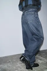 Jeans de tiro alto, estilo balloon leg, largo completo. Denim azul oscuro con efecto lavado y cinco bolsillos.