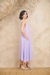 Vestido midi lila de lino, corte amplio, sin mangas y con bolsillos laterales con volados.
