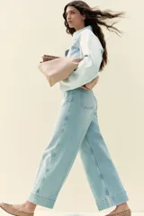 Pantalón de jean celeste de tiro alto, corte ancho, largo tobillero y bolsillos frontales con botón.