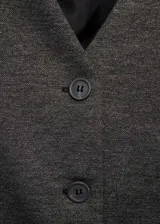 Chaleco gris con cuello en V, sin mangas y cierre frontal con botones. Diseño entallado.