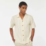 Camisa de manga corta color crema con textura de punto y botones de madera.