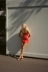 Vestido corto rojo de escote recto y hombros descubiertos, con forro interior tipo shorts y cierre trasero con cremallera oculta.