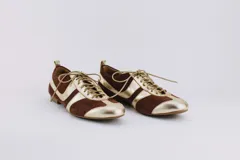 Zapato tipo ballerina acordonado, color marrón con detalles en plateado. Fabricado en cuero.