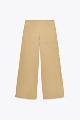 Pantalón color beige de tiro alto con cinturón ajustable con hebilla metálica. Presenta bolsillos laterales, de vivo en la pierna y de parche en la espalda.