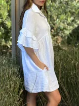 Vestido camisero azul de lino italiano, con cuello camisero, botones frontales, mangas 3/4 con doble volado y bolsillos laterales.