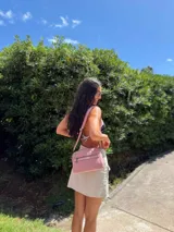 Bandolera color rosa viejo con detalles en cuero marrón claro, múltiples cremalleras metálicas y herrajes plateados. Incluye correa ancha ajustable con el logo de la marca.