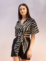 Camisa de manga corta con estampado de cebra en blanco y negro, con cuello clásico y cierre frontal con lazo.