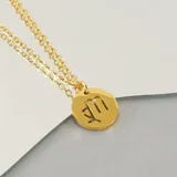 Collar dorado con dije redondo con el signo de Aries grabado.