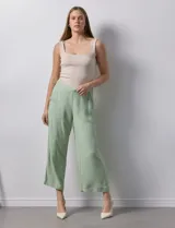 Pantalón de lino color crudo, de corte ancho y tiro alto, con bolsillos laterales y cintura elástica.