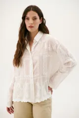 Camisa blanca con bordado floral, de corte holgado y manga larga.