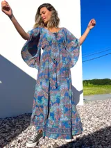 Vestido túnica largo de algodón con estampado de arabescos en tonos azules, rojos y verdes. Tiene escote en V con cordones y mangas acampanadas.