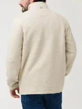 Buzo color beige con cuello alto y cierre de snaps. Diseño de rombos y parche con logo de la marca en el pecho.