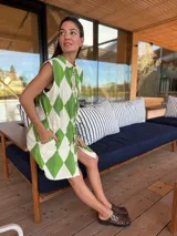 Vestido camisero corto con estampado de rombos en tonos beige, marrón y blanco. Tiene cuello camisero, cierre frontal con botones y corte holgado.