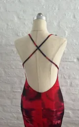 Vestido largo de tirantes finos con encaje negro en el escote y estampado abstracto en tonos rojos y negros.