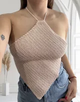 Top halter de crochet tejido en punto bajo, color rosa pálido con sutil brillo. El diseño es de forma triangular invertida, ajustado al busto y con tiras finas para atar al cuello.
