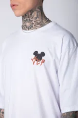 Remera blanca de algodón de corte oversize con mangas cortas y cuello redondo. Presenta un pequeño estampado en el frente con la figura de Mickey Mouse y caracteres orientales.