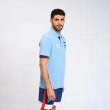 Remera polo celeste con detalles en azul marino en cuello y mangas. Escudo del Club Nacional de Football bordado en el pecho y logo de Umbro estampado en blanco.