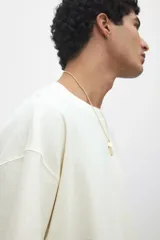 Remera color crema de punto de algodón pesado, con cuello redondo ribeteado, hombros caídos, bajo recto y corte oversized.