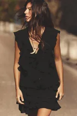 Falda pantalón corta negra con volantes y lazo lateral con abalorios. Cierre lateral con cremallera oculta y forro interior.