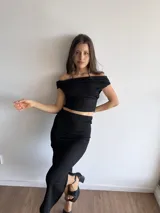Conjunto negro de bambula elastizada, compuesto por un top off-shoulder y una falda midi ajustada con abertura lateral.