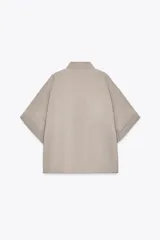 Camisa azul de cuello solapa y manga corta con dobladillo. Tiene dos bolsillos de parche en el pecho, bajo asimétrico con aberturas laterales y cierre frontal con botones ocultos.