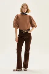 Blusa blanca de algodón con mangas abullonadas de broderie con diseño floreado. Presenta volados en el cuello y hombros, con un estilo romántico y femenino.