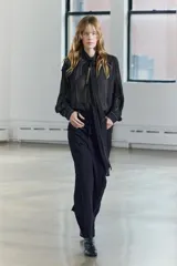 Blusa negra con cuello redondo con lazo en el mismo tejido, manga larga con puño y detalle de hilo metalizado.