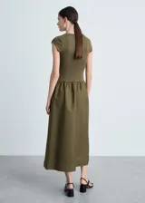 Vestido midi verde oliva con corte a la cintura y falda amplia. El cuerpo es de tejido de punto ajustado y la falda es de algodón. Tiene mangas cortas y cuello redondo.