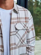 Sobrecamisa a cuadros color crema, marrón y blanco, de manga larga con cierre de botones y bolsillos en el pecho.