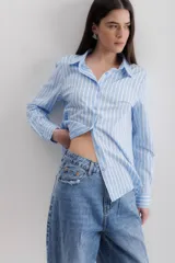 Camisa blanca a rayas verticales negras, de corte clásico, con cuello camisero y mangas largas con puños abotonados.