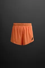 Shorts de running color naranja confeccionados en tejido técnico ligero y elástico con forro interior. Cintura elástica ajustable con cordón interior, bolsillo trasero con cierre y logo estampado en la pierna.